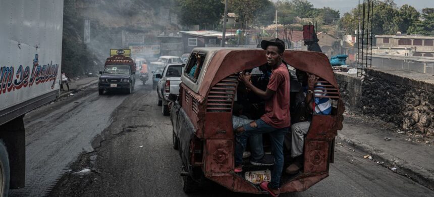 Credit: "UNOCHA/Giles Clarke A man hangs onto the back of a bus in the troubled Delmas neighbourhood of Port-au-Prince."