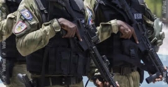 Two armed security officers in tactical vests and rifles standing side by side.