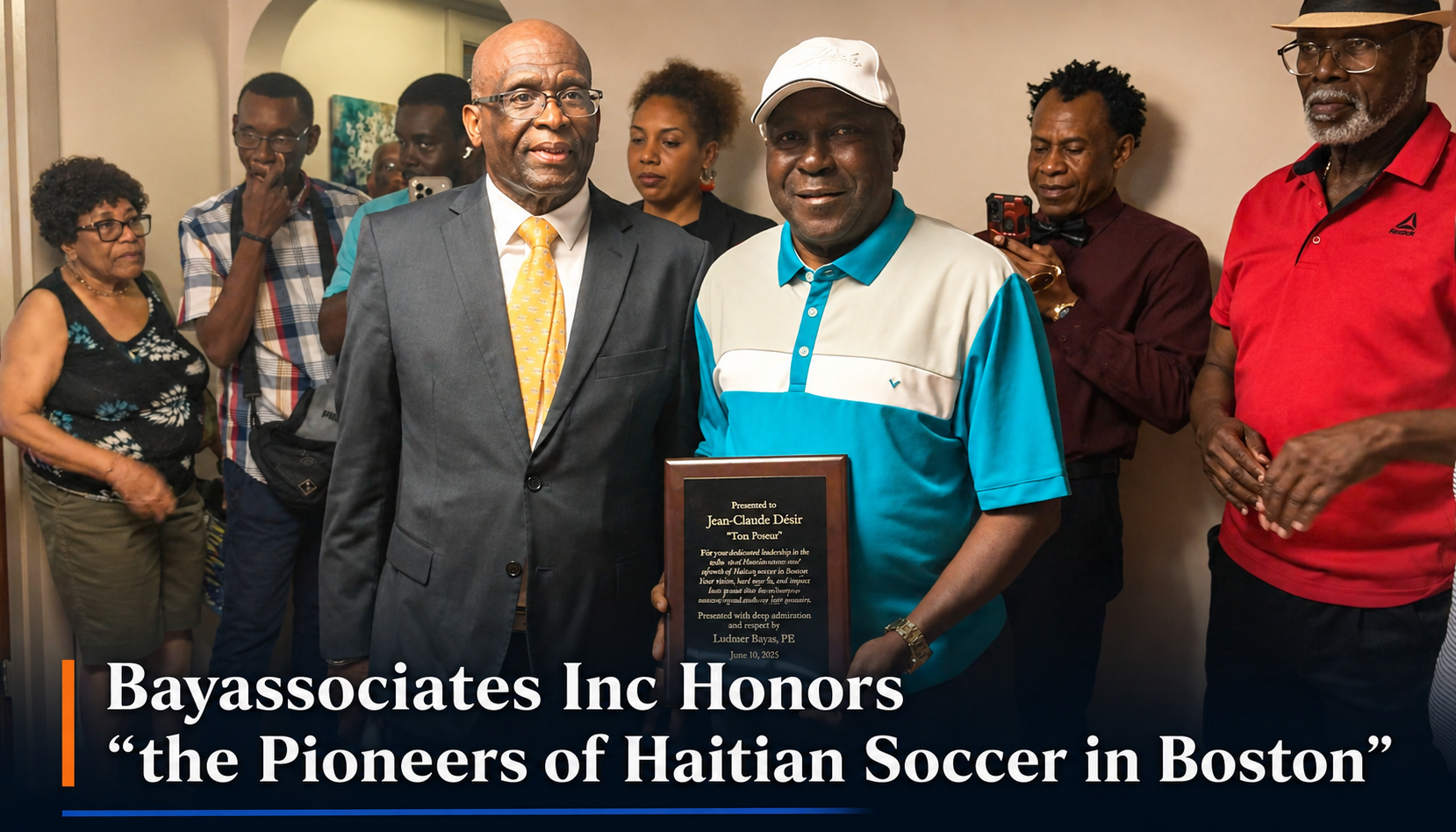 Group of Black adults at an award ceremony; man in teal polo holds a plaque, smiles, others stand around and applaud.