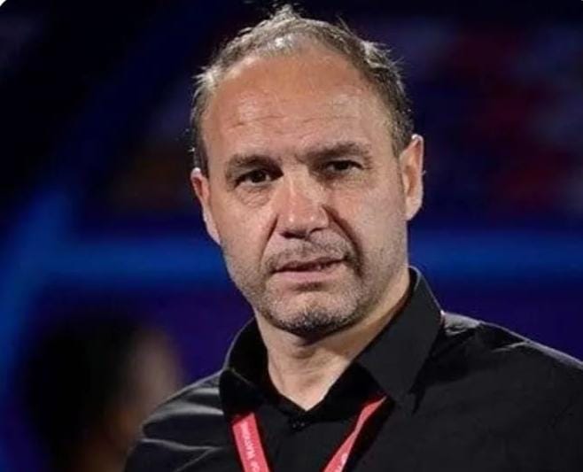 Middle-aged man in a black shirt with a red lanyard, at a conference or event.