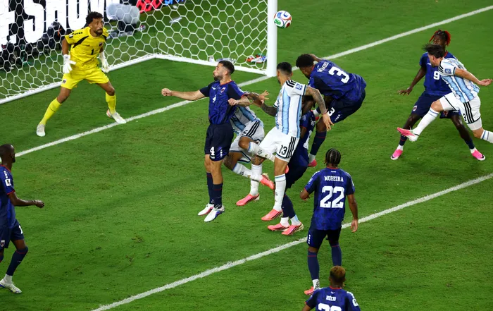 Soccer players battle near the goal as a ball nears the net, with a yellow-clad goalkeeper guarding the left side.