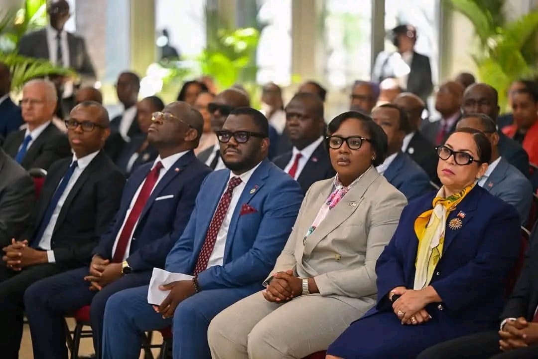 Front-row professionals in business attire seated at a formal event, listening attentively.