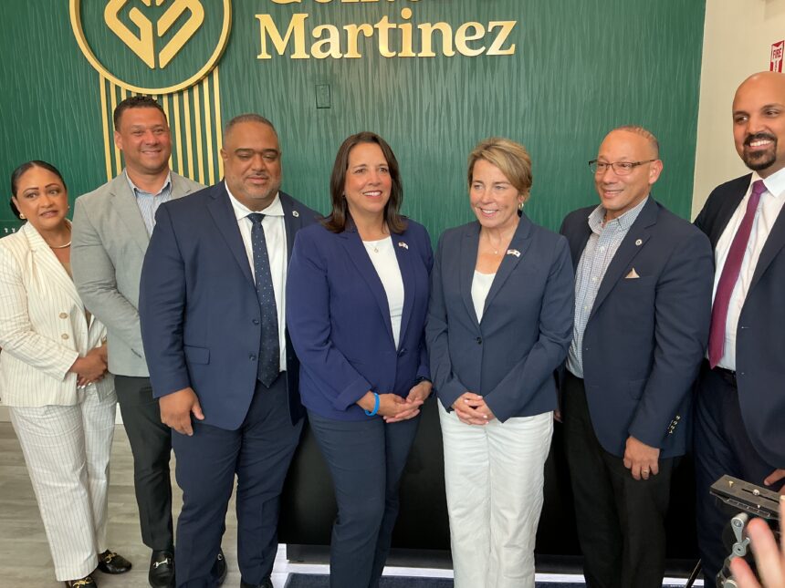 Group of professionally dressed adults posing for a photo in front of a green textured wall with a Martinez logo in the background.